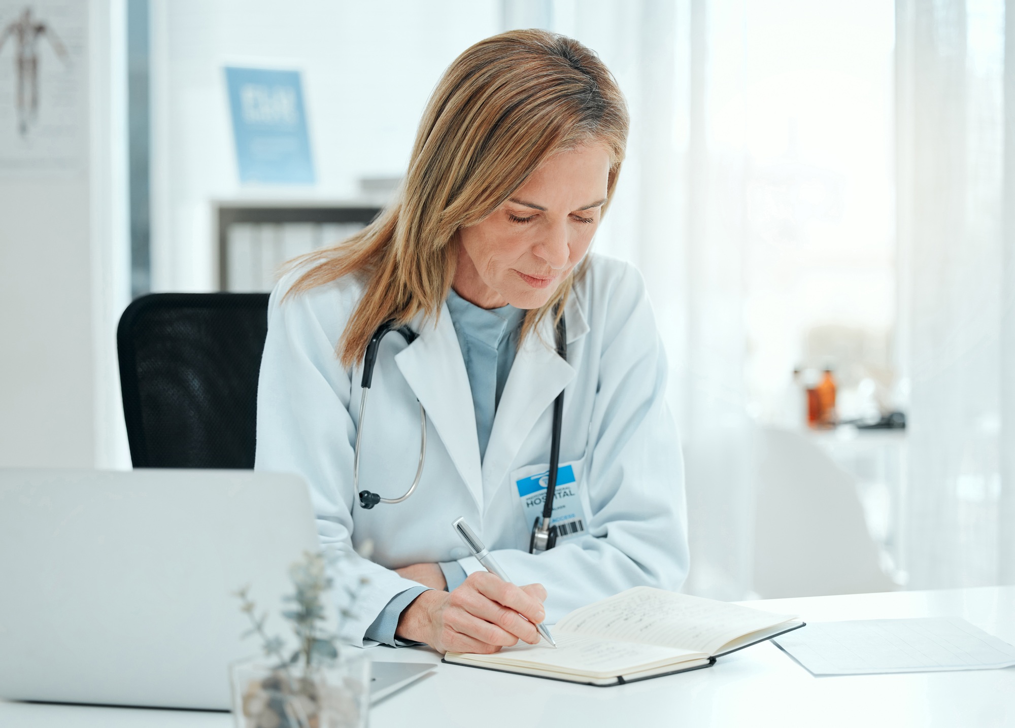 Shot of a mature doctor sitting alone in her clinic and writing notes
